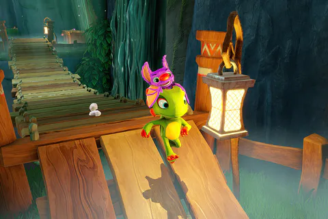 Yooka and Laylee cross a wooden bridge inside a lantern-lit cavern.
